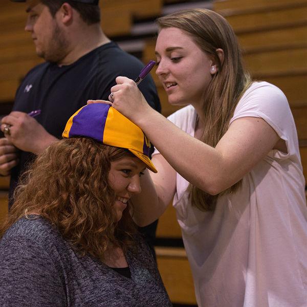 一名学生在另一名学生的HSU帽子上签名